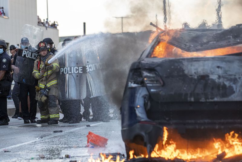 Atlanta police officers form a shield around an Atlanta firefighter as he extinguishes an Atlanta Police Department patrol car that was set aflame by protesters outside CNN Center in Atlanta, Friday, May 29, 2020. (Photo: ALYSSA POINTER / ALYSSA.POINTER@AJC.COM)