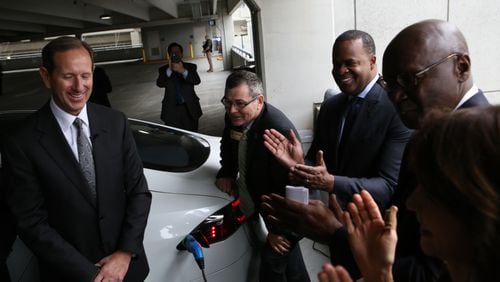 Officials ceremonially plug a Tesla into an electric vehicle charger at Hartsfield-Jackson's international terminal. Credit: Henry Taylor