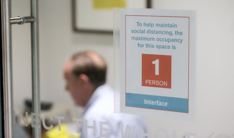 A sign warning employees about social distancing guidelines hangs in the window of a focus room at Interface’s headquarters. As workers return to offices after the COVID-19 pandemic, some will find redesigned space and new safety rules in place. (Christine Tannous / christine.tannous@ajc.com)