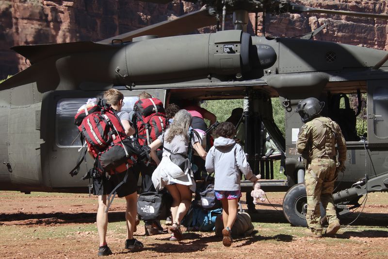 U.S. Army soldiers of the Arizona National Guard guide tourists trapped by flash flooding into a UH-60 Blackhawk, Saturday, Aug. 24, 2024, on the Havasupai Reservation in Supai, Ariz. (Maj. Erin Hannigan/U.S. Army via AP)