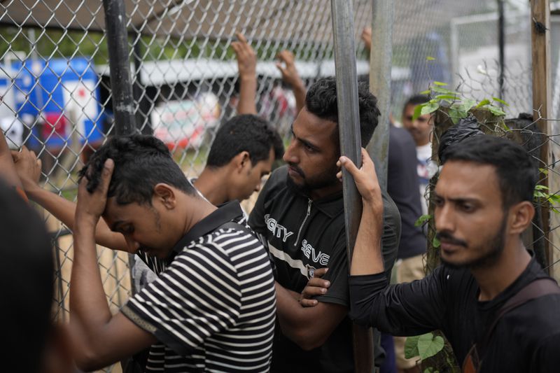 Migrants from Bangladesh wait at an immigration post where Panamanian officers process the identifications of those who have trekked across the Darién Gap, in Lajas Blancas, Panama, Thursday, Sept. 26, 2024. (AP Photo/Matias Delacroix)