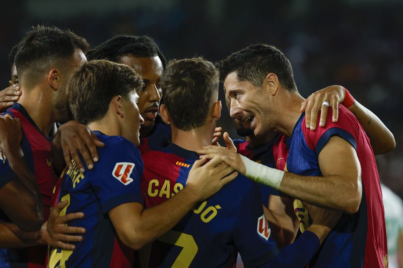 Barcelona's Robert Lewandowski, right, celebrates with teammates after scoring the opening goal during a Spanish La Liga soccer match between Barcelona and Getafe at the Olympic stadium in Barcelona, Spain, Wednesday, Sept. 25, 2024. (AP Photo/Joan Monfort)