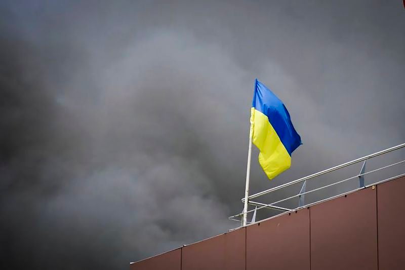 In this photo released by the Dnipro Regional Administration, Ukrainian flag waves as smoke rises after Russia's missile attack in Dnipro, Ukraine, Wednesday, July 3, 2024. (Dnipro Regional Administration via AP)