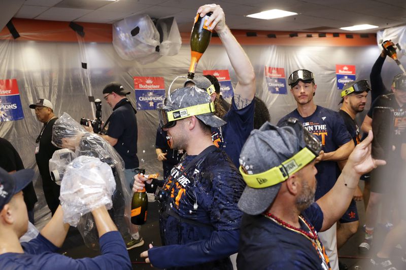 Houston Astros' Chas McCormick, center, is doused with champagne as the team celebrates in the clubhouse after defeating the Seattle Mariners 4-3 to clinch the AL West title after a baseball game Tuesday, Sept. 24, 2024, in Houston. (AP Photo/Michael Wyke)