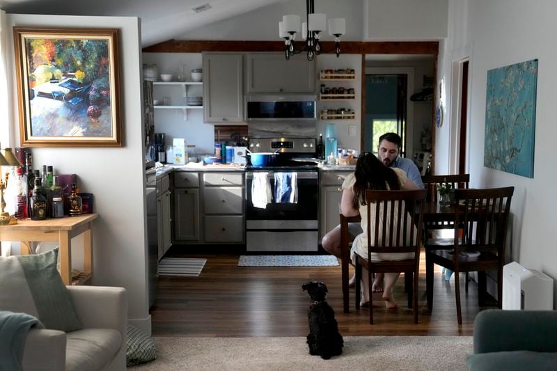 Julia and Steven Manetta eat dinner as their dog, Basil, watches closely Thursday, Aug. 29, 2024, in their Lemont, Ill., home. (AP Photo/Charles Rex Arbogast)