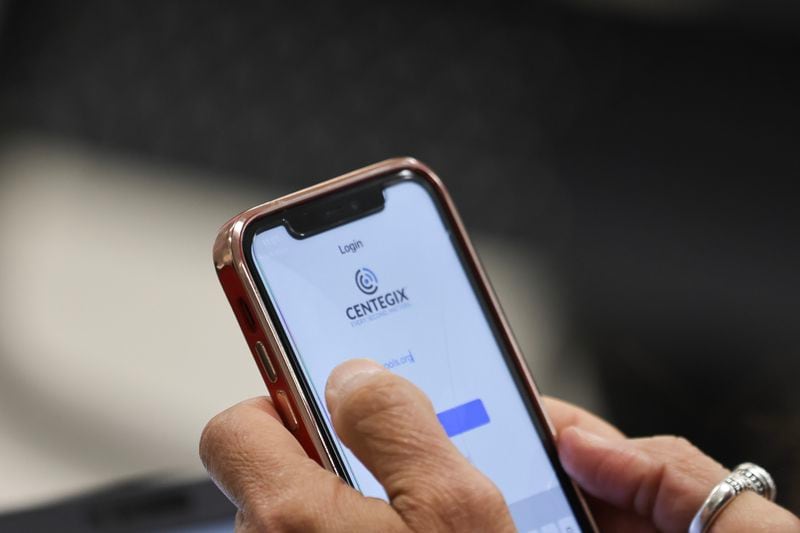 A faculty member at Findley Oaks Elementary School in Fulton County adds the Centegix app to her phone during a training on how to use the crisis alert badges on Monday, March 20, 2023. (Natrice Miller/AJC)