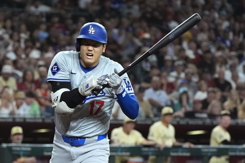 Los Angeles Dodgers designated hitter Shohei Ohtani of Japan, grimaces after being hit by a pitch against the Arizona Diamondbacks during the second inning of a baseball game, Friday, Aug. 30, 2024, in Phoenix. (AP Photo/Ross D. Franklin)