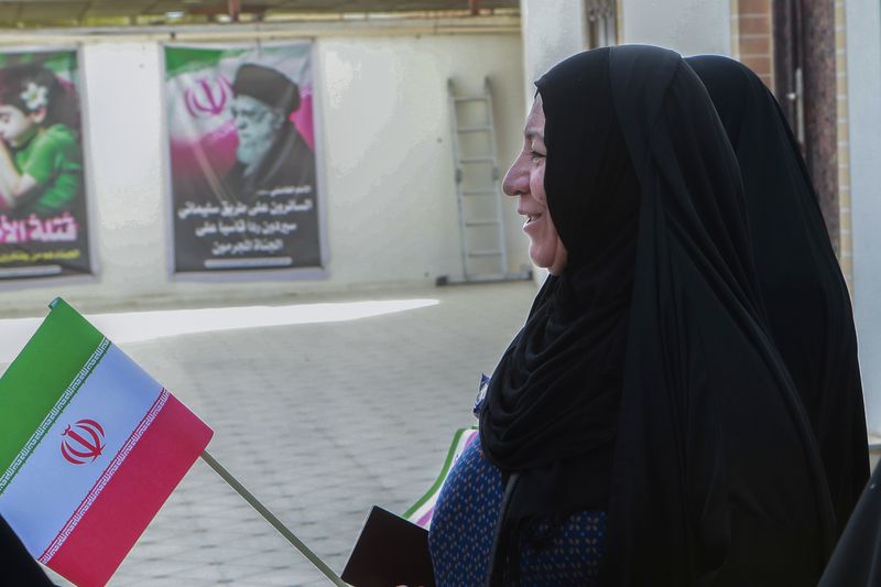 A woman prepares to casts her ballot during the presidential election at the Iranian consulate in Basra southeast of Baghdad, Iraq, Friday, June 28, 2024. Iranians are voting in a presidential election to replace the late President Ebrahim Raisi, killed in a helicopter crash in May along with the country's foreign minister and several other officials. (AP Photo/Nabil al-Jourani)