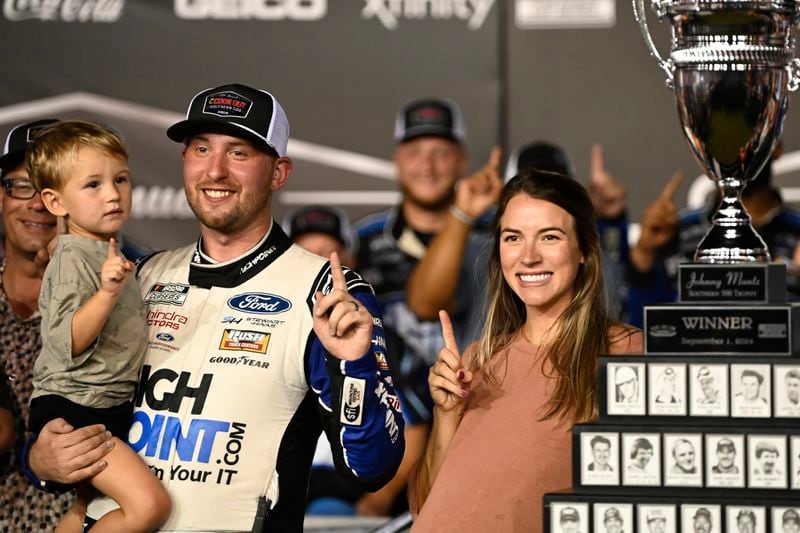 Chase Briscoe, center, celebrates in Victory Lane with his son Brooks and wife Marissa after winning a NASCAR Cup Series auto race at Darlington Raceway, Sunday, Sept. 1, 2024, in Darlington, S.C. (AP Photo/Matt Kelley)