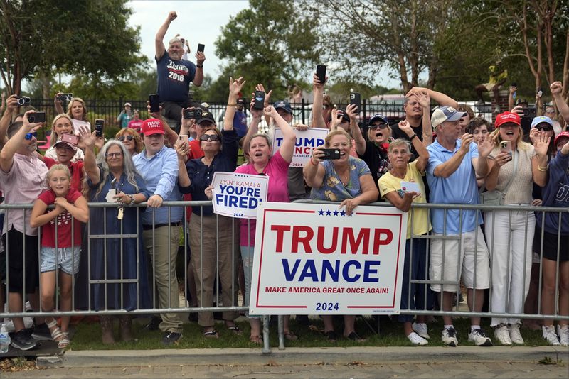 People line the road as Republican presidential nominee former President Donald Trump arrives to speak at a temporary relief shelter as he visits areas impacted by Hurricane Helene, Friday, Oct. 4, 2024, in Evans, Ga. (AP Photo/Evan Vucci)