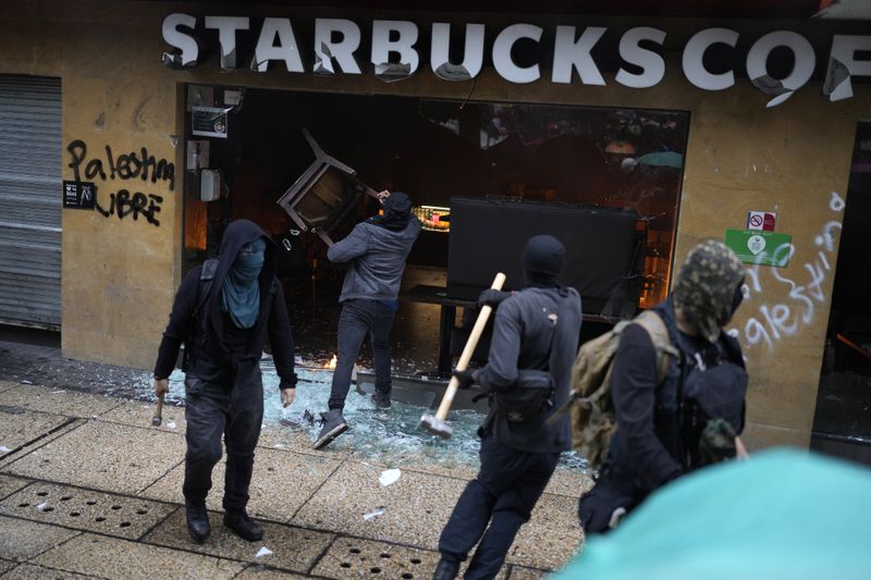 Masked youth destroy a Starbucks storefront during a march marking the 10-year anniversary of the disappearance of 43 students from an Ayotzinapa rural teacher's college, in Mexico City, Thursday, Sept. 26, 2024. (AP Photo/Eduardo Verdugo)