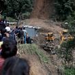 People watch earthmovers removing automobile debris and the dead bodies of victims trapped under a landslide caused by heavy rains in Kathmandu, Nepal, Sunday, Sept. 29, 2024. (AP Photo/Sujan Gurung)