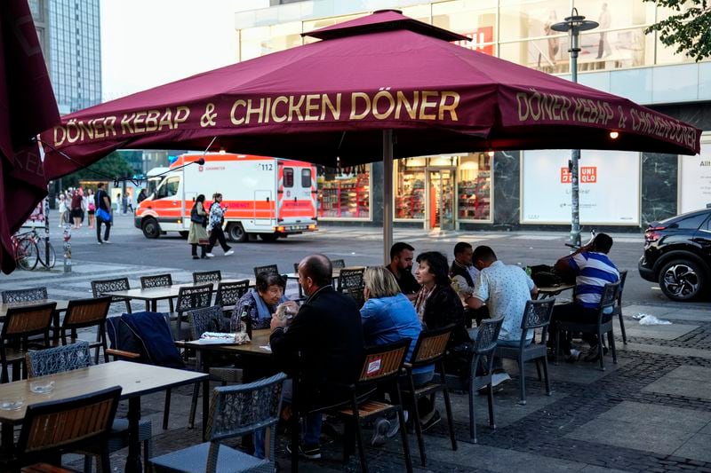 People eat doner in the outdoor area of a doner kebab restaurant in Berlin, Germany, Wednesday, Sept. 18, 2024. (AP Photo/Ebrahim Noroozi)