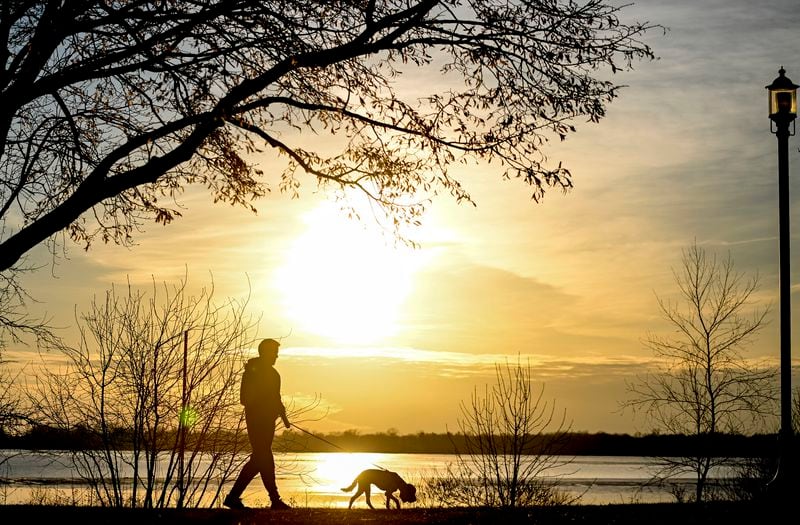 FILE - The sun sets behind a person as they walk their dog along Lac Saint-Louis in Montreal, on. March 3, 2024. (Graham Hughes/The Canadian Press via AP)