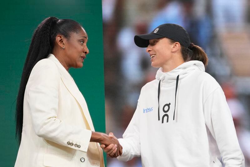 Former French athletic champion Marie-Jose Perec, left, shakes hands with French Open titleholder Poland's Iga Swiatek during the draw for the French Tennis Open at the Roland Garros stadium, Thursday, May 23, 2024 in Paris. The tournament starts Sunday May 26, 2024. (AP Photo/Thibault Camus)