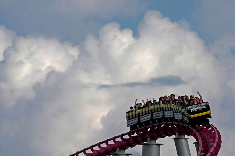 FILE - People ride on the Mamba roller coaster at Worlds of Fun theme park as storm clouds build in the distance on June 21, 2024, in Kansas City, Mo. (AP Photo/Charlie Riedel, File)