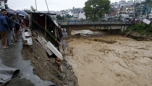 People gather at the edge of the Bagmati River in spate after heavy rains in Kathmandu, Nepal, Saturday, Sept. 28, 2024. (AP Photo/Gopen Rai)