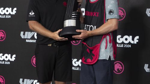 First-place individual champion Tyrrell Hatton, left, of Legion XIII, and caddie Hugo Dobson, right, celebrate with the trophy after winning during the final round of LIV Golf Nashville at The Grove, Sunday, June 23, 2024, in College Grove, Tenn. (Sam Greenwood/LIV Golf via AP)