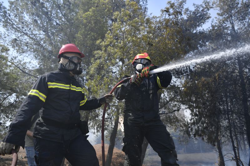 Firefighters operate in Dioni, northeast of Athens, Greece, Monday, Aug. 12, 2024. Hundreds of firefighters backed by dozens of water-dropping planes and helicopters were battling the flames from first light Monday, with a major forest fire that began the previous day raging out of control on the fringes of Athens, fanned by strong winds. (AP Photo/Michael Varaklas)