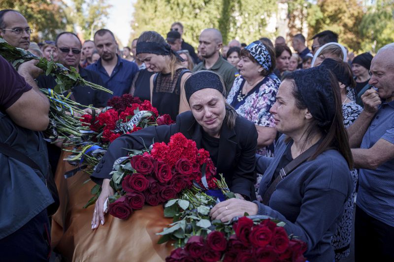 Relatives cry near the coffin of a Ukrainian serviceman killed in a Russian rocket attack at a Ukrainian military academy, during the funeral ceremony in Poltava, Ukraine, Saturday Sept. 7, 2024. (AP Photo/Evgeniy Maloletka)