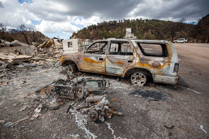 A charred car sits among the remains of the Swiss Chalet Hotel after it was destroyed by the South Fork Fire in the mountain village of Ruidoso, N.M., Saturday, June 22, 2024. (AP Photo/Andres Leighton)