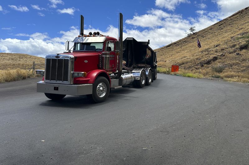 A truck exits from a temporary dump site in Lahaina, Hawaii on Thursday, July 18, 2024, where debris from last year's deadly fire is being stored. (AP Photo/Jennifer Sinco Kelleher)