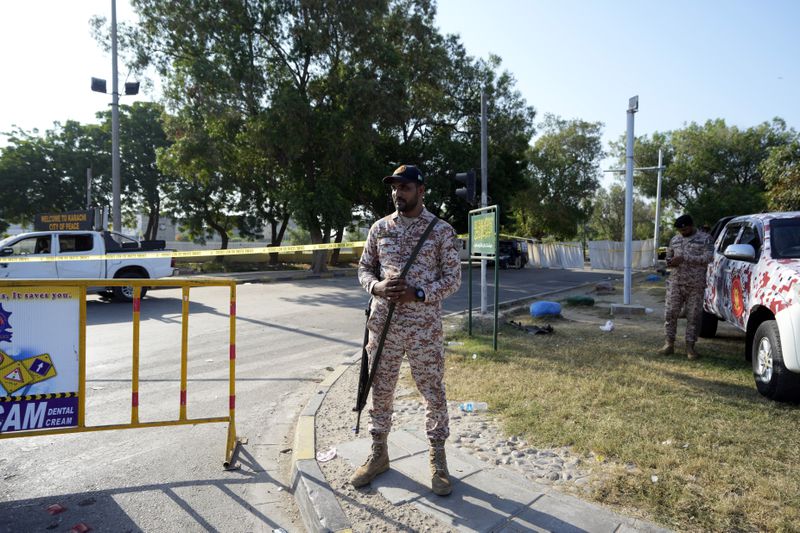 Security officials stand guard next to the site of an explosion that caused injures and destroyed vehicles outside the Karachi airport, Pakistan, Monday, Oct. 7, 2024. Pakistani Baloch separatists claim deadly bomb attack that killed 2 Chinese near Karachi airport. (AP Photo/Fareed Khan)