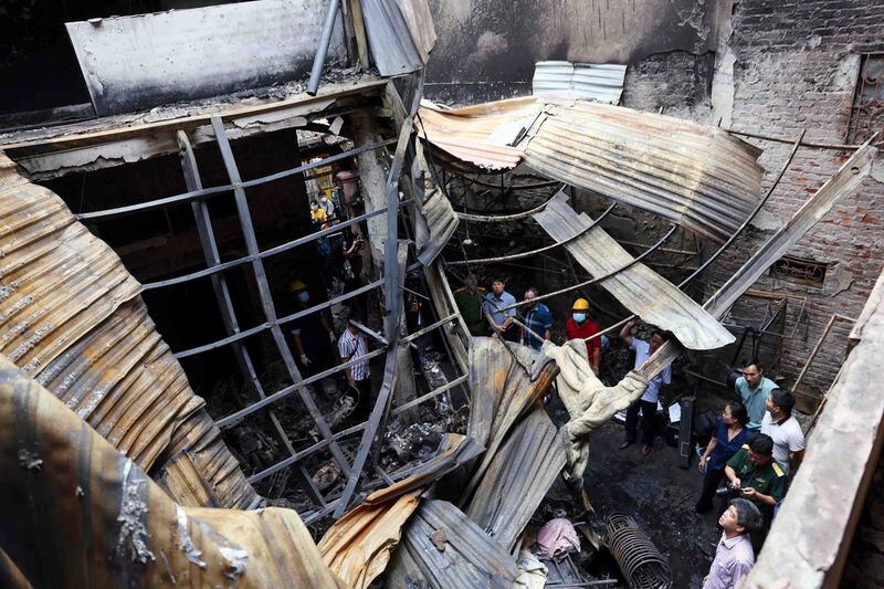 Officials visit the site of a house fire in Hanoi, Vietnam Friday, May 24, 2024. Authorities said the fire has killed a number of people and injured a few others. (An Van Dang/VNA via AP)