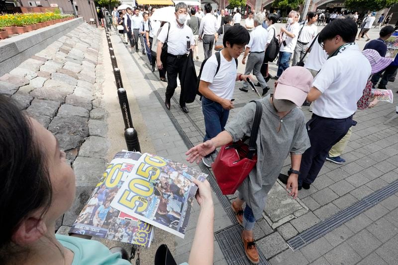 Pedestrians line up to obtain an extra edition of the Sports Nippon newspaper reporting on the Los Angeles Dodgers' Shohei Ohtani becoming the first player in major league history with 50 home runs and 50 stolen bases in a season, Friday, Sept. 20, 2024, in Tokyo. (AP Photo/Eugene Hoshiko)