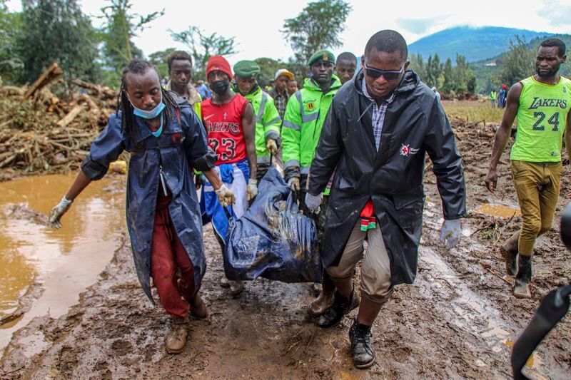 FILE - Kenya Red Cross workers and volunteers, carry a man's body retrieved from mud, after floodwater washed away houses, in Kamuchiri Village Mai Mahiu, Nakuru County, Kenya, Tuesday, April 30, 2024. The impact of the calamitous rains that struck East Africa from March to May was intensified by a mix of climate change and rapid growth of urban areas, an international team of climate scientists said in a study. (AP Photo/Patrick Ngugi, File)