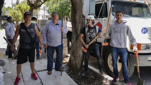 Arturo Hernandez, second from right, poses next to members of The Tree Army, a group that works to improve the urban forest, after breaking concrete placed on the roots of a tree in Mexico City, Monday, Aug. 26, 2024. (AP Photo/Eduardo Verdugo)