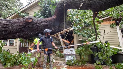 A crew at work removing a fallen tree from an Atlanta area home after Helene swept through the area.