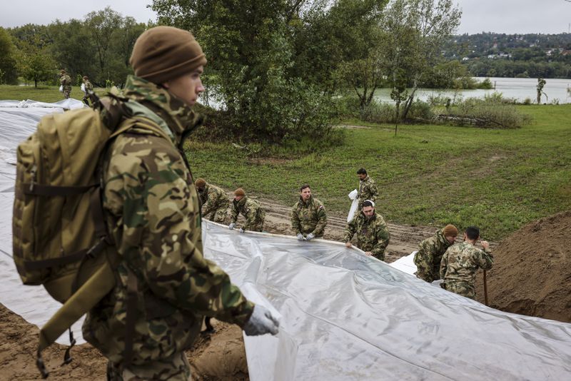 Soldiers build barriers with sandbags against flood water at the bank of Danube River in Pilismarot, Hungary, Monday, Sept. 16, 2024. (Robert Hegedus/MTI via AP)