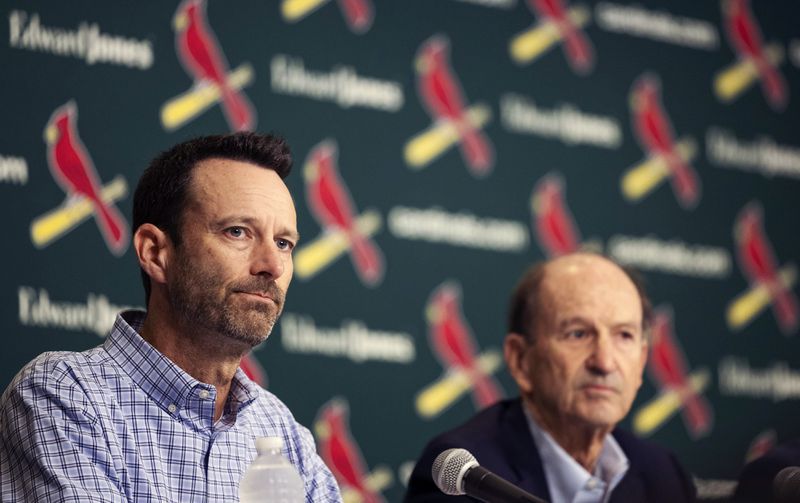 St. Louis Cardinals Chairman and Chief Executive Officer Bill DeWitt Jr., left, reads a statement at the beginning of a press conference as his father, Bill DeWitt, looks on Monday, Sept. 30, 2024, at Busch Stadium in St. Louis. (Zachary Linhares/St. Louis Post-Dispatch via AP)