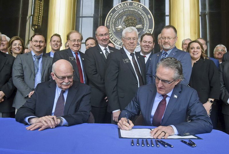 FILE - State legislators and officials watch April 26, 2019 as Gov. Doug Burgum signs Senate Bill 2001, which authorizes a $50 million endowment for the proposed Theodore Roosevelt Presidential Library and Museum in Medora. Seated at left is Secretary of State Al Jaeger who certified the bill. (Tom Stromme/The Bismarck Tribune via AP, File)