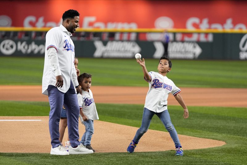 Texas Rangers former player Elvis Andrus, left, who announced his retirement earlier Friday, stands with his daughter Lucia, left rear, and Michael, center, as Elvis Jr., right, throws out the ceremonial first pitch before a baseball game between the Los Angeles Angels and Rangers, Friday, Sept. 6, 2024, in Arlington, Texas. (AP Photo/Tony Gutierrez)