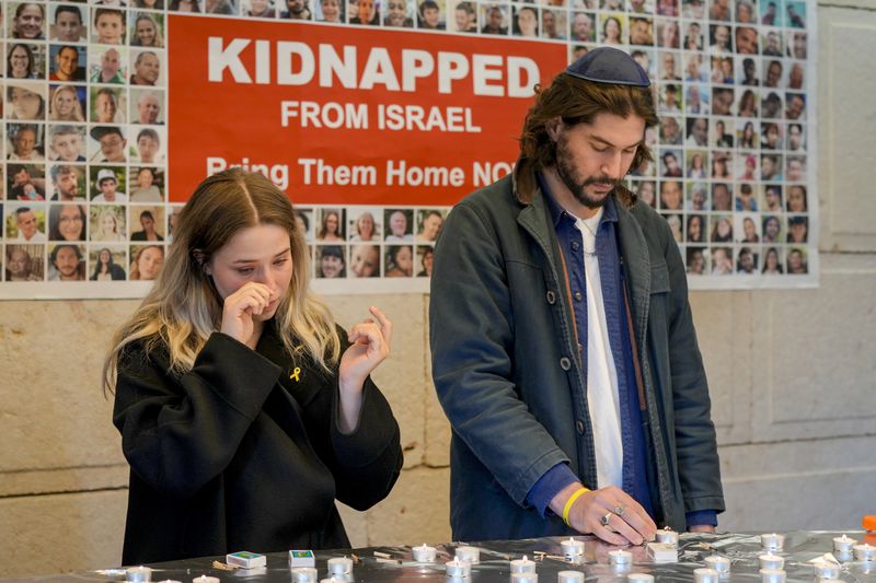 People light candles at a ceremony marking the first anniversary of the Hamas spearheaded attacks on Israel, at the synagogue of the Chabad community in Berlin, Germany, Monday, Oct. 7, 2024. (AP Photo/Markus Schreiber)