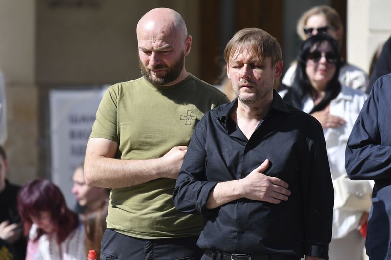 Yaroslav Bazylevych, right, prays during the funeral ceremony for his family members in Lviv, Ukraine, Friday, Sept. 6, 2024. Bazylevych's wife Yevgenia and their three daughters - Darina, 18, Emilia, 7, and Yaryna, 21 - were killed in Wednesday's Russian missile attack. (AP Photo/Mykola Tys)