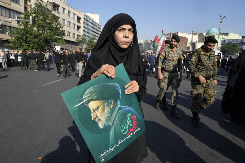 A woman holds a poster of the late Iranian President Ebrahim Raisi during a funeral ceremony for him and his companions who were killed in a helicopter crash on Sunday in a mountainous region of the country's northwest, in Tehran, Iran, Wednesday, May 22, 2024. Iran's supreme leader presided over the funeral Wednesday for the country's late president, foreign minister and others killed in the helicopter crash, as tens of thousands later followed a procession of their caskets through the capital, Tehran. (AP Photo/Vahid Salemi)