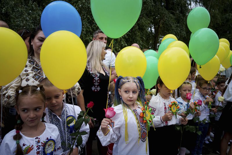 First-grades hold balloons during the traditional ceremony for the first day of school in Zaporizhzhia, Ukraine, Sunday Sept. 1, 2024. Zaporizhzhia schoolchildren celebrated the traditional first day of school near the frontline. With the front just 40 kilometers away, the war is never far from the minds of teachers and families. (AP Photo/Evgeniy Maloletka)