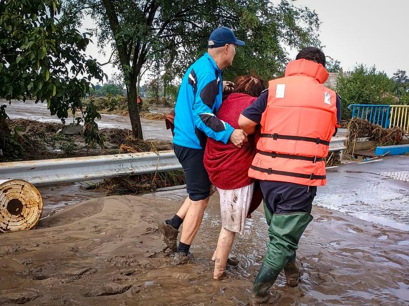 In this photo released by the Romanian Emergency Services Galati (ISU Galati), rescuers assist a local person on a flooded street in Pechea, Romania, Saturday, Sept. 14, 2024 after torrential rainstorms left scores of people stranded in flooded areas. (Romanian Emergency Services - ISU Galati via AP)