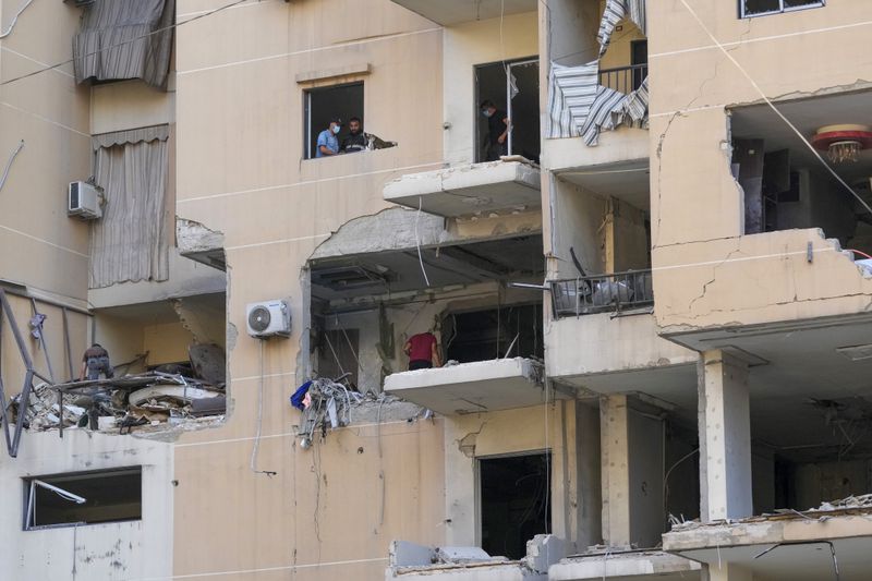 Residents and rescuers check a building that was hit by an Israeli airstrike in Beirut's southern suburbs, Thursday, Sept. 26, 2024. (AP Photo/Hassan Ammar)