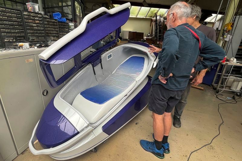 Philip Nitschke, front, stands next to a 'suicide pod' known as 'The Sarco' in Rotterdam, The Netherlands, July 8, 2024. (AP Photo/Ahmad Seir)