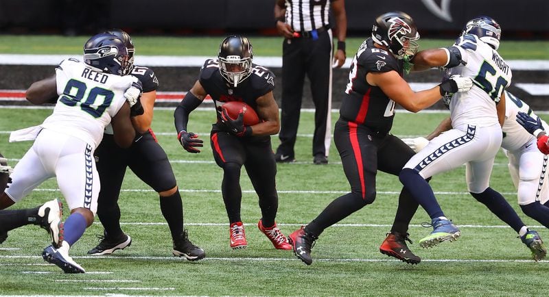 091320 Atlanta: Atlanta Falcons  lineman Matt Hennessy (left) and Chris Lindstrom (right) give Todd Gurley some running room in the season opener against the Seattle Seahawks Sunday, Sept. 13, 2020, in Atlanta.  (Curtis Compton / Curtis.Compton@ajc.com)