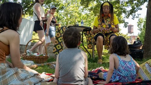 A mom and her two kids listen to a story. Atlanta residents celebrate at the Oakland Cemetary Juneteenth Family Festival. This is the third Juneteenth since becoming a federal holiday in 2021. Saturday, June 15, 2024 (Ben Hendren for the Atlanta Journal-Constitution)