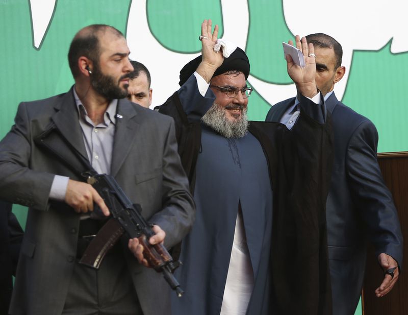 FILE - Hezbollah leader Hassan Nasrallah, center, escorted by his bodyguards, waves to a crowd of tens of thousands of supporters during a rally in Beirut's southern suburbs, Monday Sept. 17, 2012. (AP Photo/Hussein Malla, File)