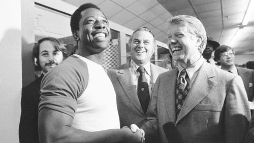 FILE - Georgia Gov. Jimmy Carter, right, and Delaware Gov. Sherman Tribbitt say hello to Atlanta Braves Hank Aaron, left, following a rain canceled game with the Los Angeles Dodgers in Atlanta, Ga., Sept. 27, 1973. (AP Photo, File)