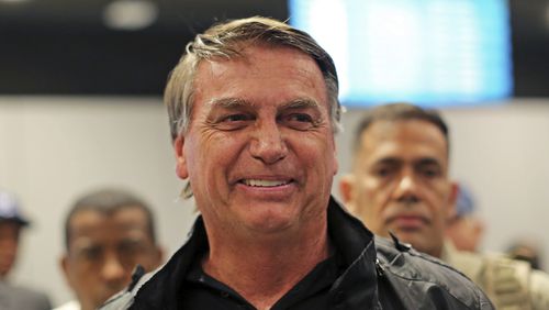 Former Brazilian President Jair Bolsonaro smiles after deplaning at the international airport in Florianopolis, Santa Catarina state, Brazil, Friday, July 5, 2024. Brazilian police have indicted Bolsonaro for money laundering and criminal association in connection with undeclared diamonds the far-right leader received from Saudi Arabia during his time in office, according to a source with knowledge of the accusations. (AP Photo/Heuler Andrey)