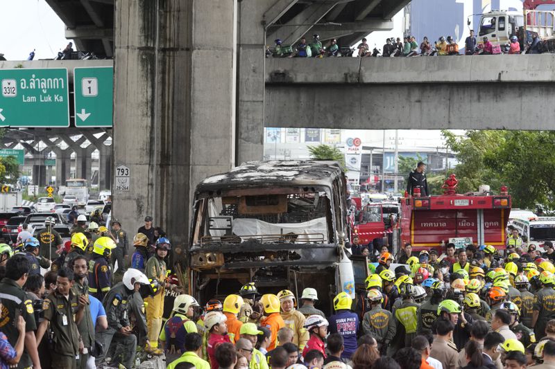 Rescuers gather at the site of a bus that caught fire, carrying young students with their teachers, in suburban Bangkok, Tuesday, Oct. 1, 2024. (AP Photo/Sakchai Lalit)