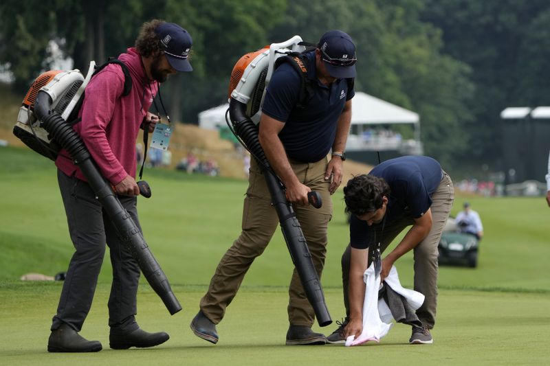 Workers clean up the 18th green after protesters ran onto it during the final round of the Travelers Championship golf tournament at TPC River Highlands, Sunday, June 23, 2024, in Cromwell, Conn. (AP Photo/Seth Wenig)